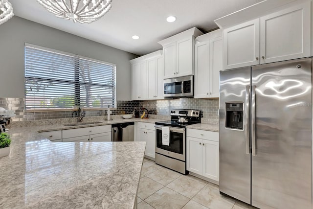 kitchen with sink, appliances with stainless steel finishes, white cabinets, and tasteful backsplash