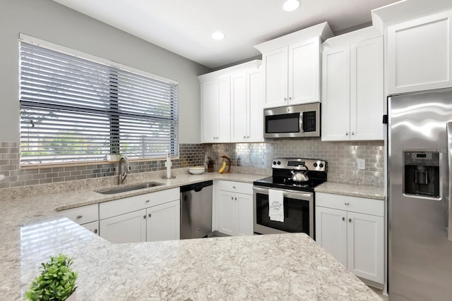 kitchen featuring backsplash, white cabinetry, light stone countertops, sink, and stainless steel appliances