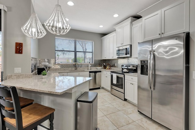 kitchen featuring white cabinetry, kitchen peninsula, stainless steel appliances, and pendant lighting