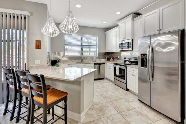 kitchen with a breakfast bar area, pendant lighting, white cabinets, and stainless steel appliances