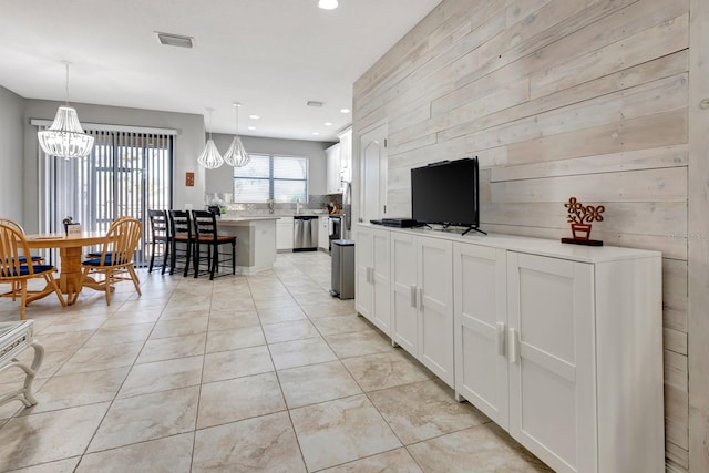 living room featuring wooden walls, light tile patterned flooring, and a notable chandelier