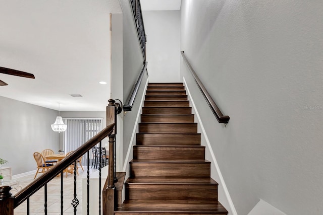 stairway featuring a notable chandelier