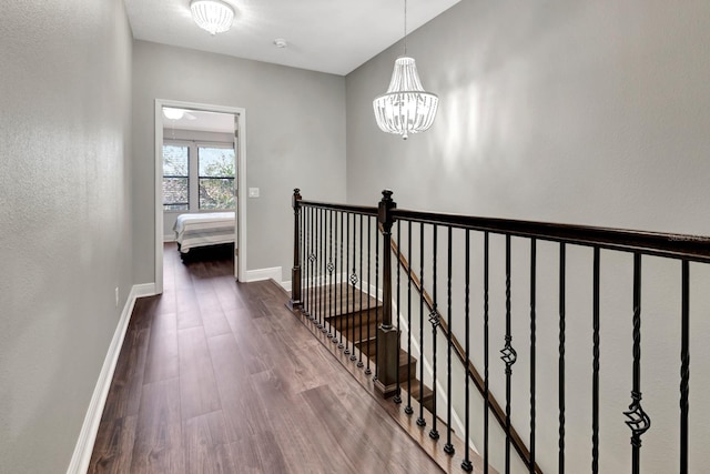 corridor with hardwood / wood-style floors and a chandelier