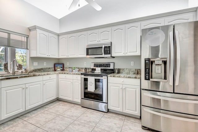 kitchen with sink, white cabinets, light stone countertops, light tile patterned flooring, and stainless steel appliances