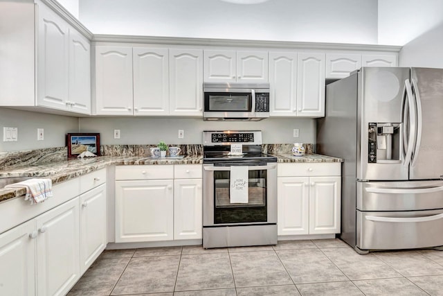 kitchen with light stone counters, white cabinets, light tile patterned floors, and stainless steel appliances