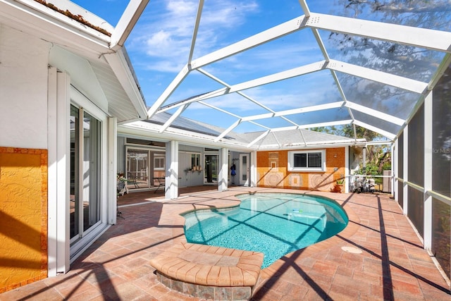 view of pool with glass enclosure and a patio area