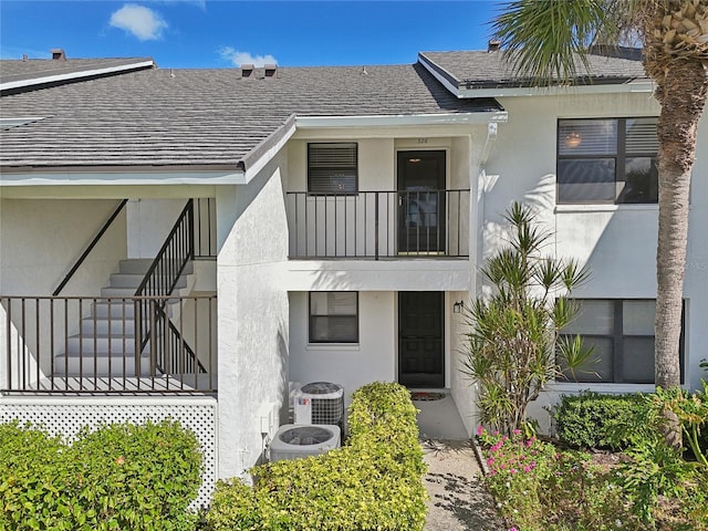 view of front of home with central AC unit and a balcony