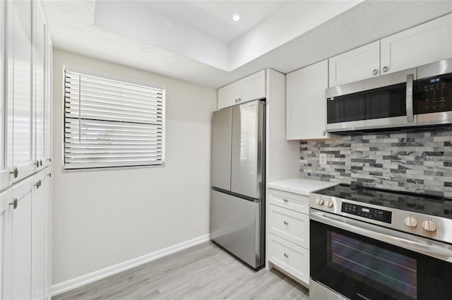 kitchen with white cabinetry, light hardwood / wood-style floors, stainless steel appliances, and tasteful backsplash