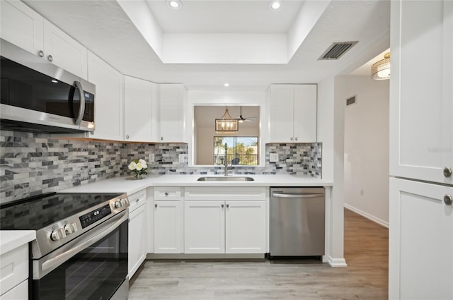 kitchen featuring light hardwood / wood-style flooring, sink, white cabinetry, appliances with stainless steel finishes, and tasteful backsplash