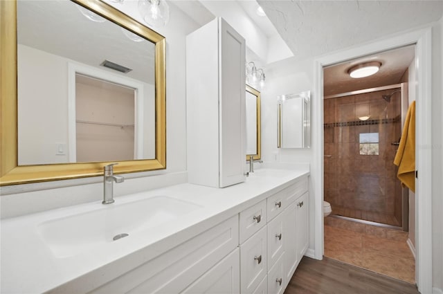 bathroom featuring toilet, a shower with shower door, hardwood / wood-style floors, and vanity