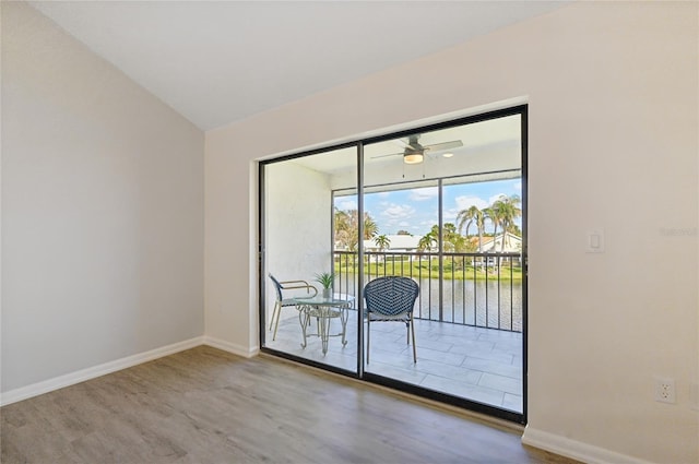 doorway with hardwood / wood-style floors, a water view, and ceiling fan