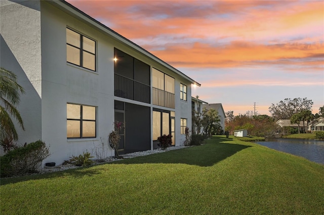 property exterior at dusk featuring a lawn