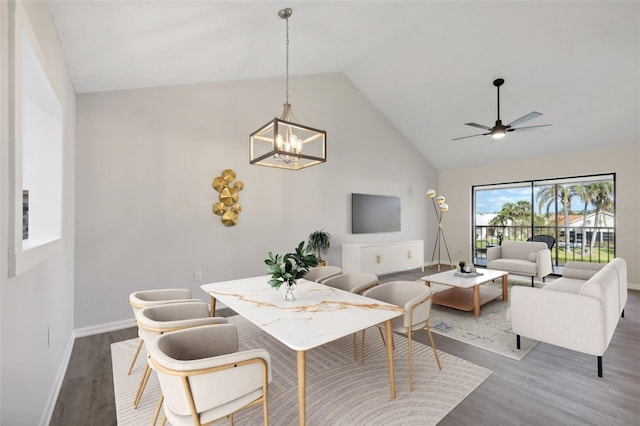 dining area with high vaulted ceiling, ceiling fan with notable chandelier, and hardwood / wood-style floors