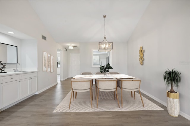 dining space featuring lofted ceiling, a chandelier, sink, and wood-type flooring