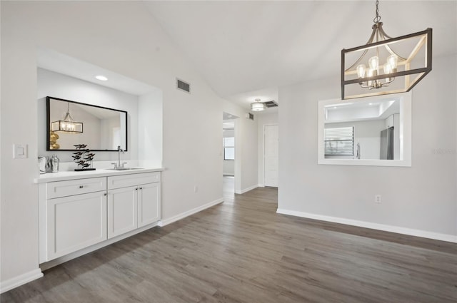 unfurnished living room with a chandelier, sink, dark wood-type flooring, and lofted ceiling