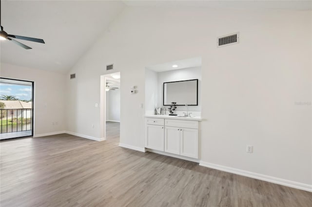 spare room featuring light hardwood / wood-style flooring, high vaulted ceiling, and sink