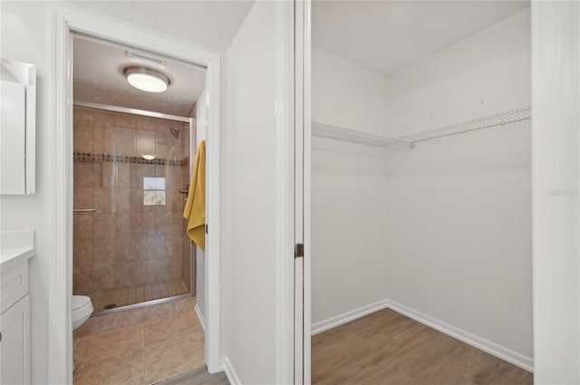 bathroom featuring a tile shower, toilet, hardwood / wood-style flooring, and vanity