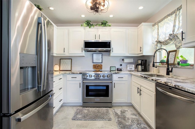 kitchen with white cabinetry, stainless steel appliances, light stone countertops, and sink