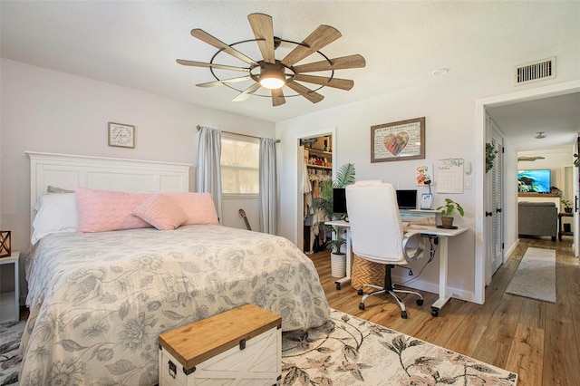 bedroom with a closet, ceiling fan, a spacious closet, and light wood-type flooring