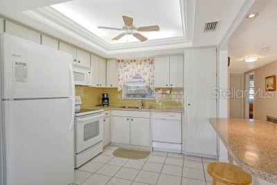 kitchen with decorative backsplash, white cabinetry, a tray ceiling, and white appliances