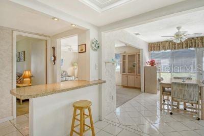 kitchen featuring light tile patterned floors, a kitchen bar, and ceiling fan