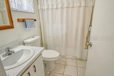 full bathroom with vanity, shower / bath combo, toilet, and tile patterned flooring