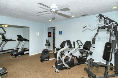 exercise room with ceiling fan and a textured ceiling