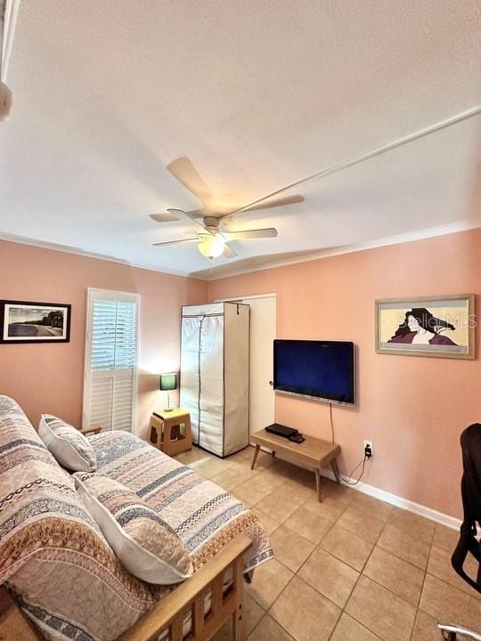 bedroom featuring ceiling fan, crown molding, and light tile patterned floors