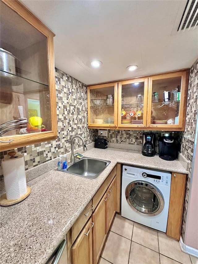 interior space featuring tasteful backsplash, visible vents, glass insert cabinets, washer / clothes dryer, and a sink