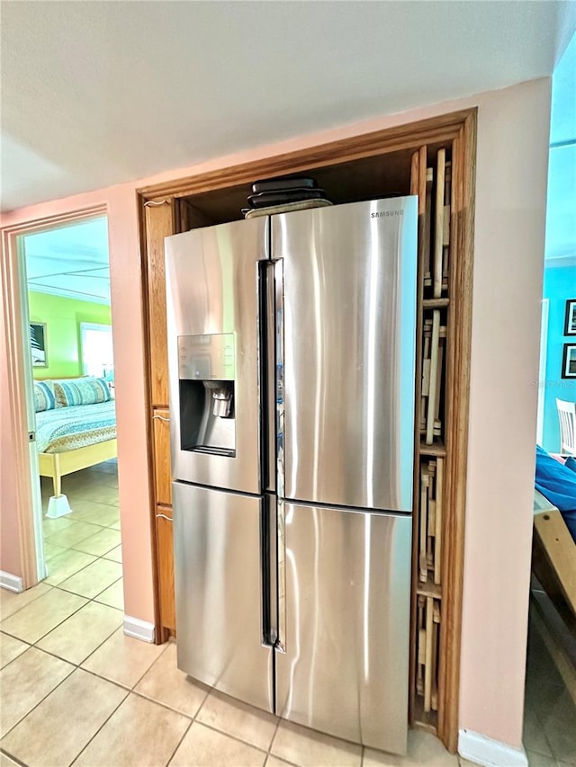 kitchen with light tile patterned floors, stainless steel fridge with ice dispenser, and baseboards