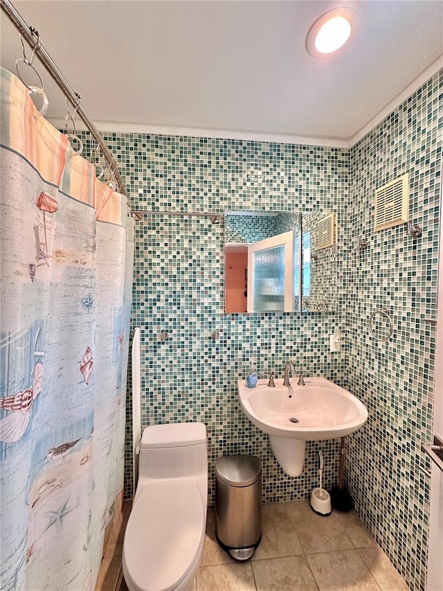 full bath featuring toilet, a shower with curtain, tile patterned floors, and tile walls