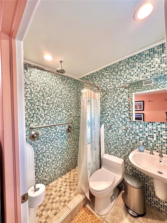 bathroom featuring a shower stall, toilet, tile patterned floors, and tile walls