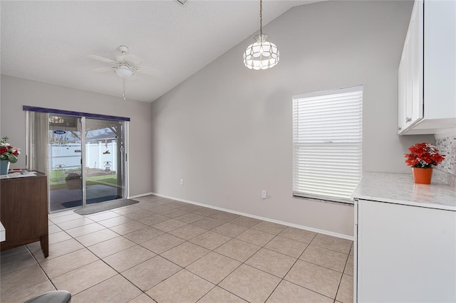 tiled dining room with ceiling fan and vaulted ceiling