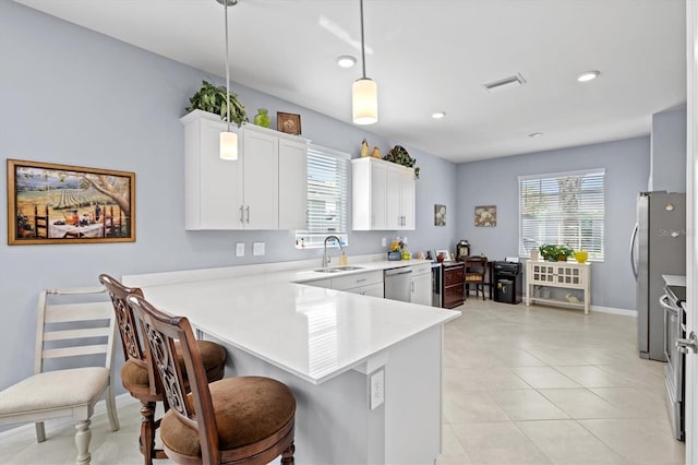 kitchen featuring kitchen peninsula, white cabinetry, a kitchen bar, sink, and decorative light fixtures