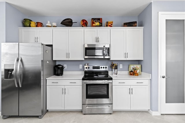 kitchen with appliances with stainless steel finishes, white cabinets, and light tile patterned floors