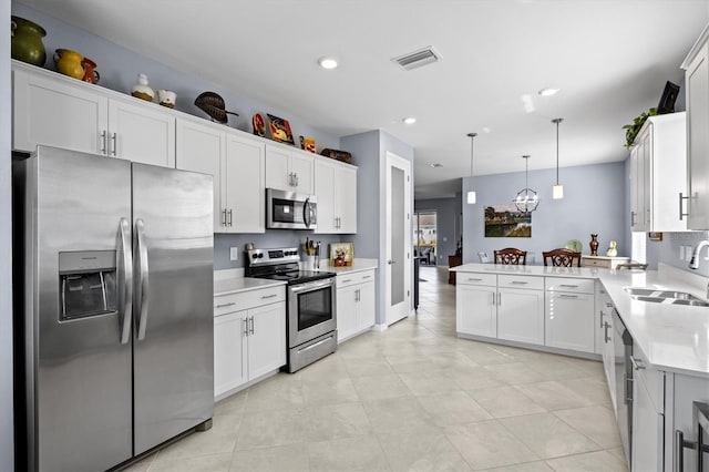 kitchen with sink, kitchen peninsula, stainless steel appliances, decorative light fixtures, and white cabinets