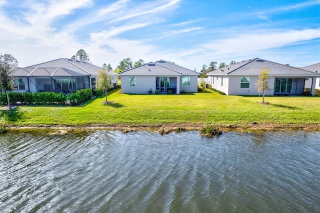 back of property with a lanai, a lawn, and a water view