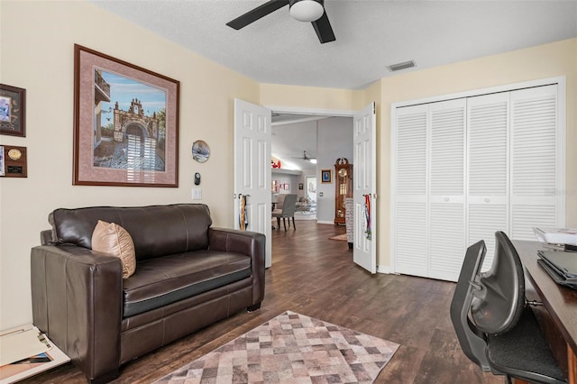 living room featuring a textured ceiling, dark hardwood / wood-style floors, and ceiling fan