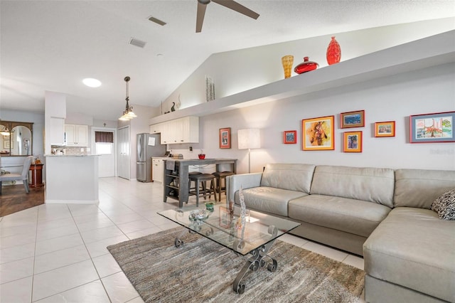 tiled living room featuring ceiling fan and vaulted ceiling