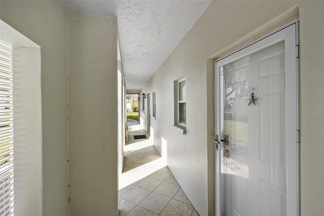 hall with light tile patterned flooring and a textured ceiling