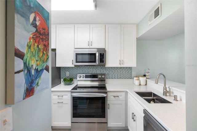 kitchen featuring appliances with stainless steel finishes, decorative backsplash, white cabinets, and sink