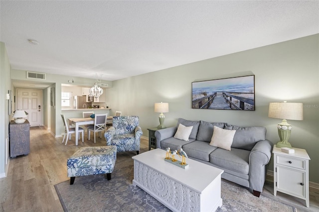 living room featuring a notable chandelier, hardwood / wood-style floors, and a textured ceiling