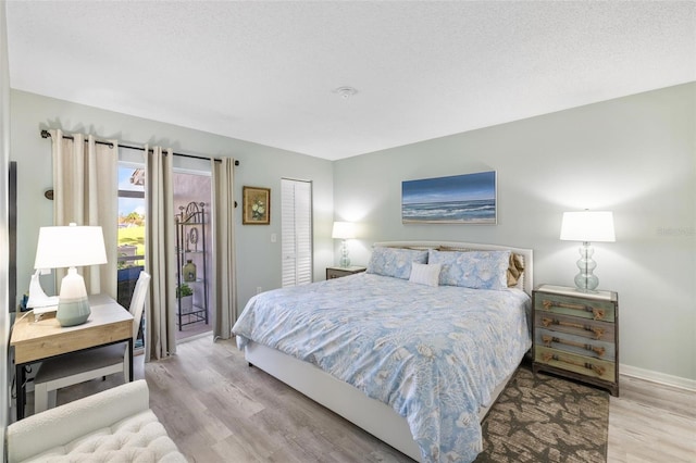 bedroom featuring a closet, a textured ceiling, access to outside, and light hardwood / wood-style flooring