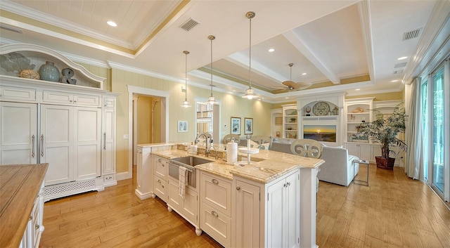 kitchen featuring ceiling fan, sink, a center island with sink, white cabinetry, and hanging light fixtures