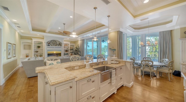 kitchen with sink, ceiling fan with notable chandelier, decorative light fixtures, a fireplace, and a center island with sink