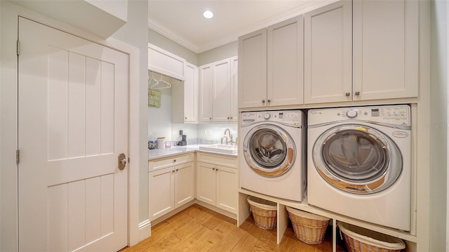 washroom featuring cabinets, sink, crown molding, washer and dryer, and light hardwood / wood-style floors