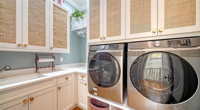 clothes washing area featuring ornamental molding, sink, cabinets, and independent washer and dryer