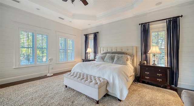 bedroom with hardwood / wood-style floors, ceiling fan, and a raised ceiling