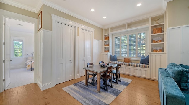 office area with built in shelves, light hardwood / wood-style floors, and crown molding