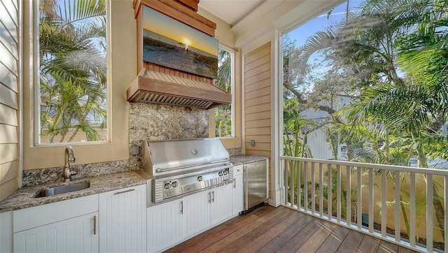 wooden terrace with exterior kitchen, sink, and grilling area